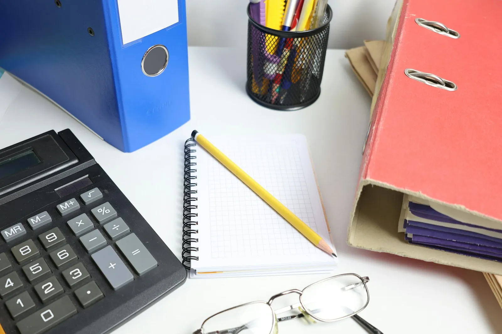 Bureau avec calculatrice, classeurs, carnet et lunettes — planification de budget